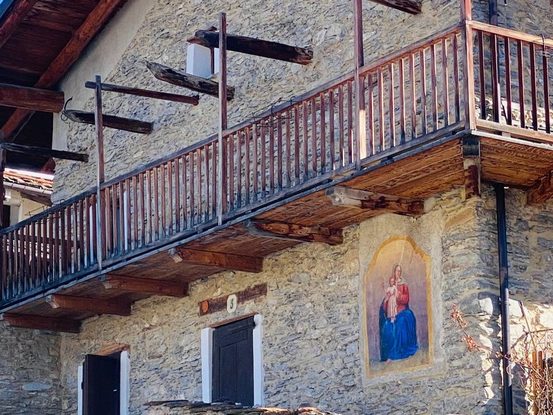 Casa in pietra con balconata in legno e affresco mariano
